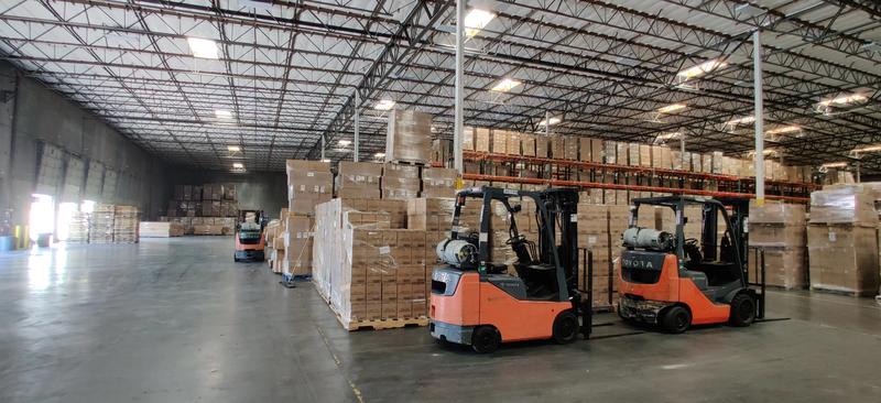 Warehouse interior with stacked pallets and fork trucks for efficient storage and logistics management.