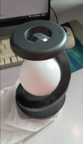 Rotating Moon Desk Lamp with Wireless Charging on a desk, showcasing its sleek design and charging capabilities.