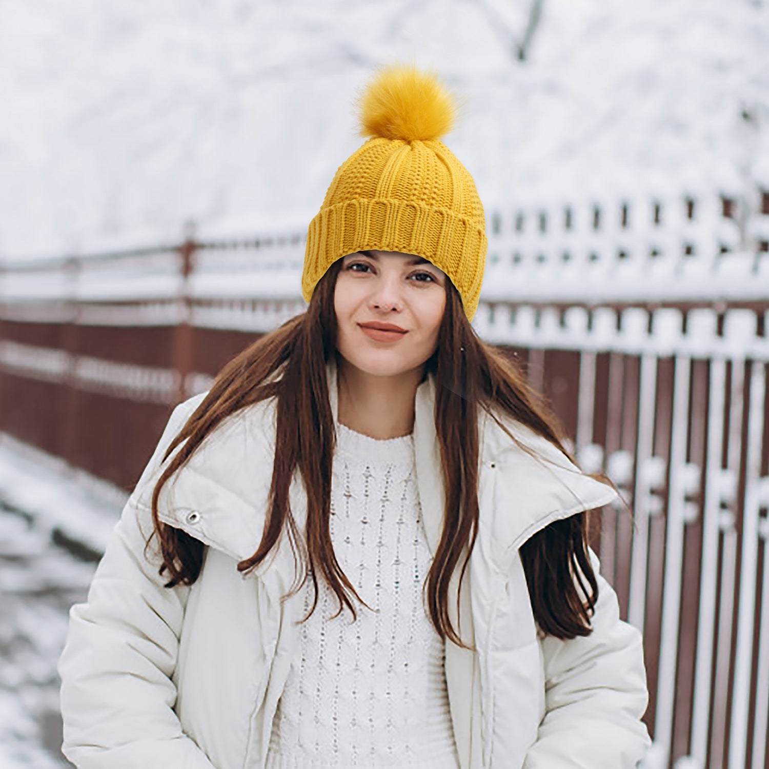 Winter Knitted Hats Fashion Stretchy Lined Skull Hats For Women Faux Fur Pom Pom Hat Keep Warming Beanie Hat in yellow on a snowy day.