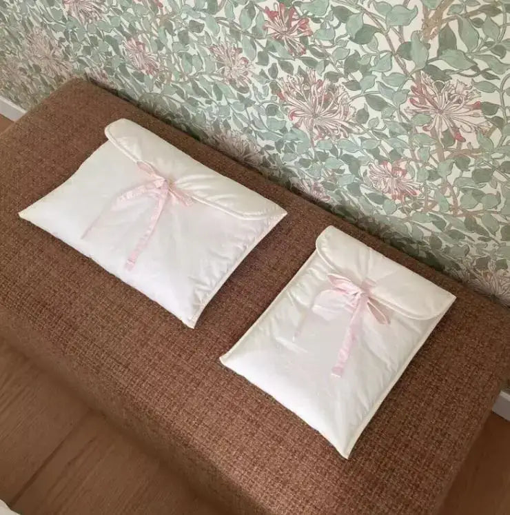Two elegant quilted bags with pink ribbons on a brown bench, perfect for storage and organization.